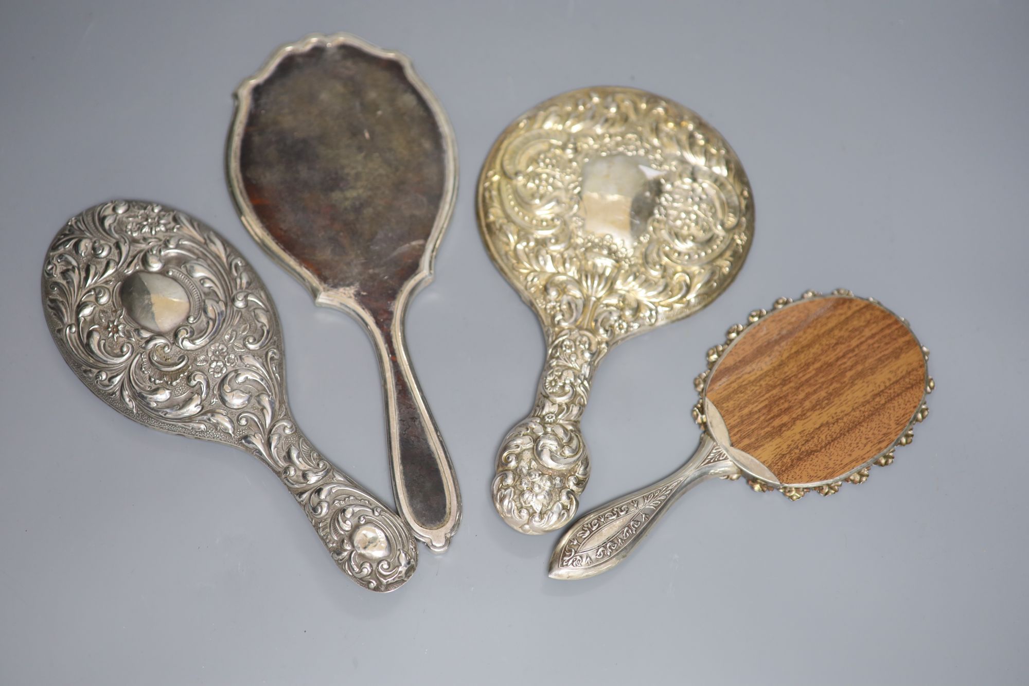 Four assorted hand mirrors including two silver and two white metal, largest 31cm.